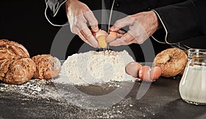 Baker breaking eggs into a heap of baking flour