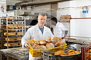 Baker carrying fresh bread in box
