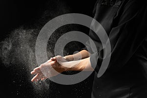 Baker, chef making cotton with flour, freezing flour in the air. Banner, on a black background. Splash of flour. Cooking bread,