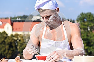 Baker concept. Cook or chef with muscular shoulders and chest covered with flour. Man on busy face wears cooking