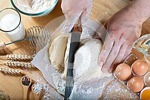 Baker cuts the dough with a knife bread, pizza or pie recipe ingredients with hands, food on kitchen table background, working wit