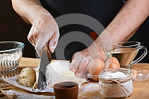 Baker cuts the dough with a knife bread, pizza or pie recipe ingredients with hands, food on kitchen table background, working wit