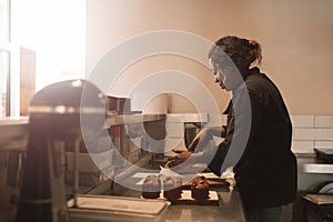 Baker cutting brownies at the counter of a commercial kitchen