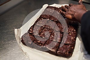 Baker cutting brownies into squares in a cafe kitchen