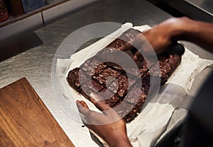 Baker cutting up fresh brownies in a cafe kitchen