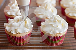 Baker decorates muffins with cream and confectionery nozzles