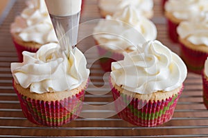 Baker decorates muffins with cream and confectionery nozzles photo