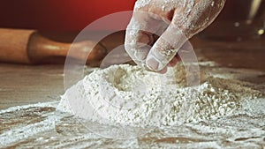 Baker hand preparing flour on the table to make dough, slow motion, 240 fps. Cooking and backing preparation. Food