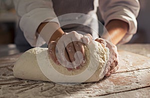 Baker hands kneads dough in the morning