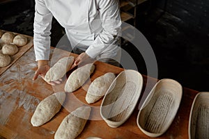 Baker hands preparing formed bread dough for proofing