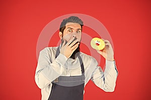 Baker hold donut. Funny hipster. Bearded man cook. Chef man in cafe. Diet and healthy food. Bearded man eat doughnut