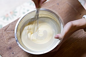 Baker holding the bowl while whisking flour