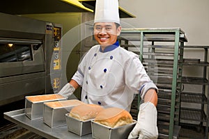 Baker holding fresh bread from oven