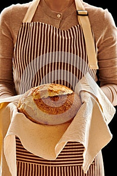 Baker holding loaf of homemade bread