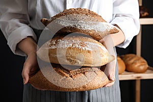 Baker holding loaves of bread indoors
