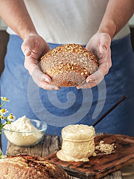 Baker holds homemade craft organic bread fresh from the oven, prepared from flour, yeast, salt and water. Homemade baking in the