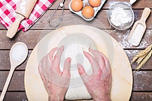 Baker knead dough bread, pizza or pie recipe ingridients with hands, food flat lay on kitchen table background. Working with flour