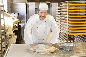 Baker kneading dough in bakery photo