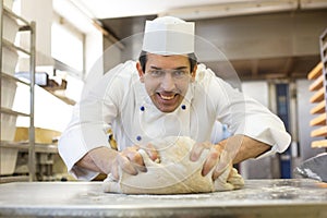 Baker kneading dough in bakery