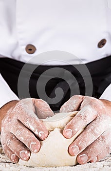 Baker kneading dough with his hands