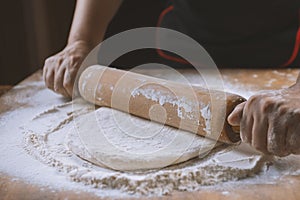 Baker pours flour for making pizza. Chef cooking dough to bake a cake on a wooden table.