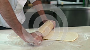 Baker kneading dough with a rolling pin at his kitchen