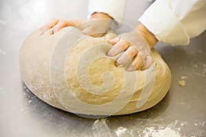 Baker kneading fresh bread dough in bakery