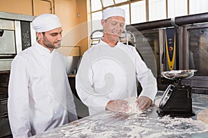 Baker looking his colleague kneading dough
