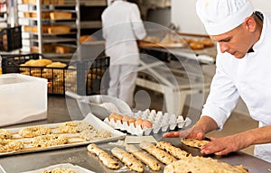 Baker makes buns and other sweet pastries from dough