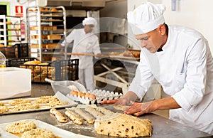 Baker makes buns and other sweet pastries from dough