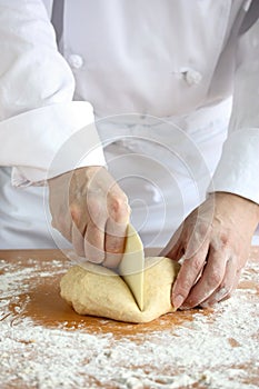 Baker making bread,cutting a dough