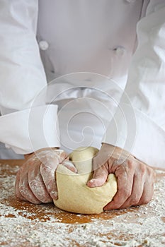 Baker making bread, kneading a dough photo