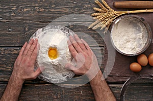 Baker making dough on a rustic dark wooden table