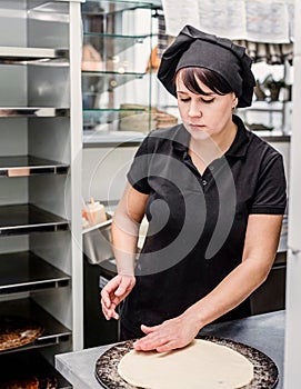 Baker making pizza at the pizzeria kitchen