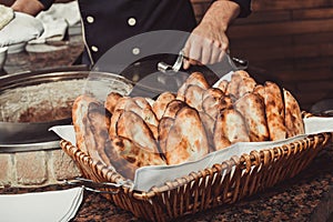 Baker making turkish pita bread in tandoor, clay oven. Baking process. Many fresh hot bread in the basket.