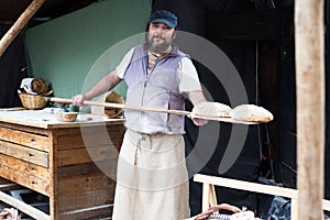 Baker posing with shovel and grain dough
