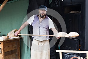 Baker  posing with shovel and grain dough