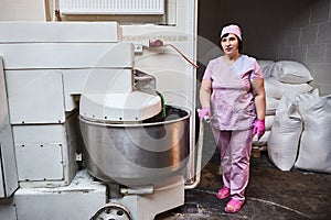 Baker mix dough with professional kneader machine at the manufacturing. Equipment for making flour products