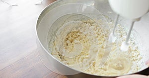 Baker mixing ingredients in bowl cooking dough baking cake using electric mixer.