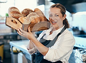 Baker, pastry chef and cafe owner carrying a tray of fresh rolls and bread loaf assortment in a coffee shop. Portrait of