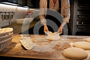 Baker portioning dough with bench cutter at bakery