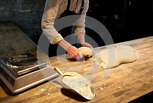 Baker portioning dough with bench cutter at bakery