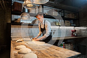 Baker portioning dough with bench cutter at bakery