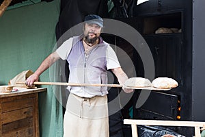Baker posing with shovel and grain dough