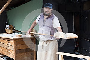 Baker posing with shovel and grain dough