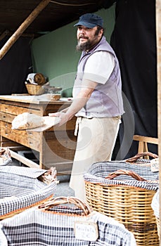 Baker posing with shovel and grain dough