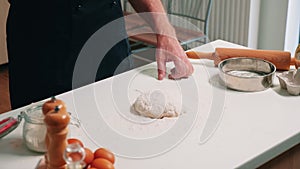 Baker pouring flour on dough for bread