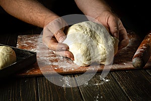 The baker prepares or kneads the dough for baking buns with his hands. The concept of baking confectionery or pies in the bakery