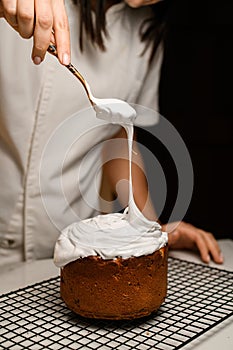 Baker puts white cream on the Easter cake