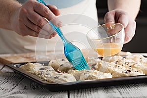 Baker putting whisked egg coat on top of freshly rolled up mini